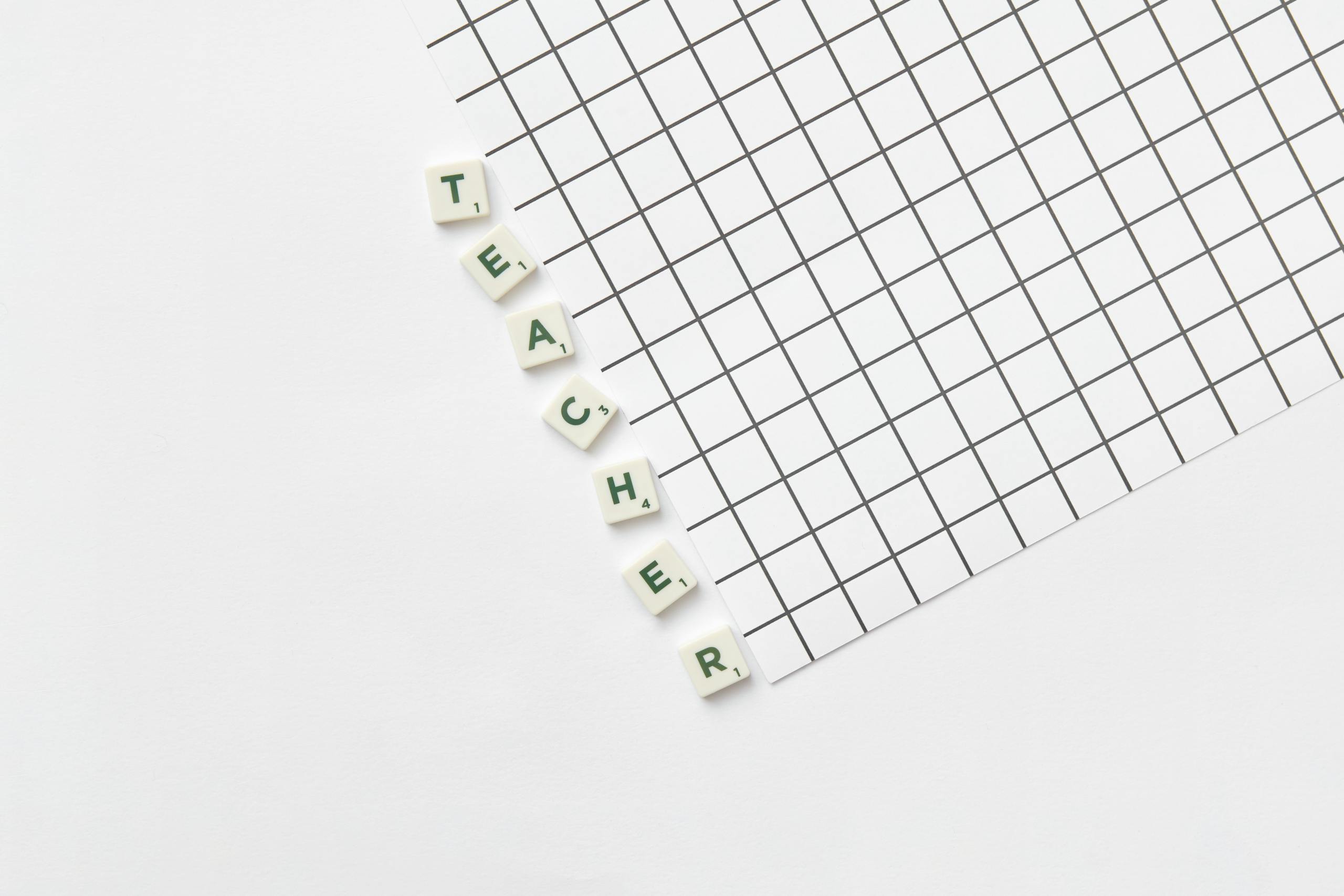 Alphabet letters spelling 'Teacher' on a white grid paper, highlighting education theme.